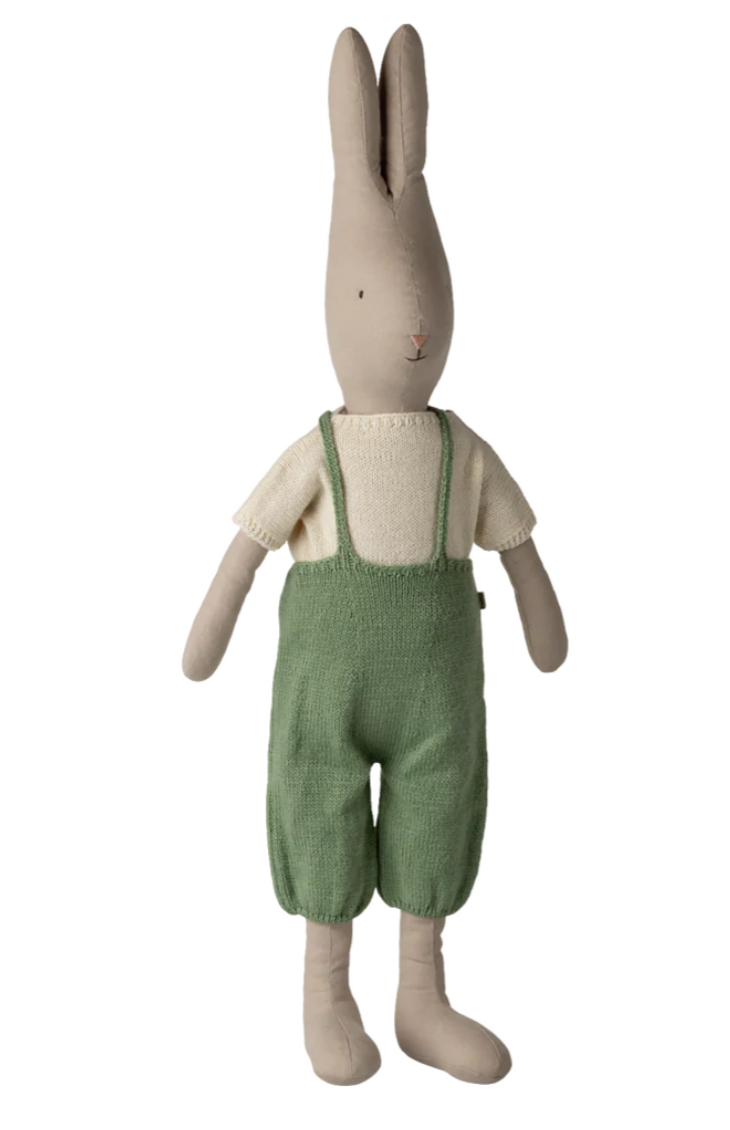 Stuffed rabbit toy wearing green overalls on a white background